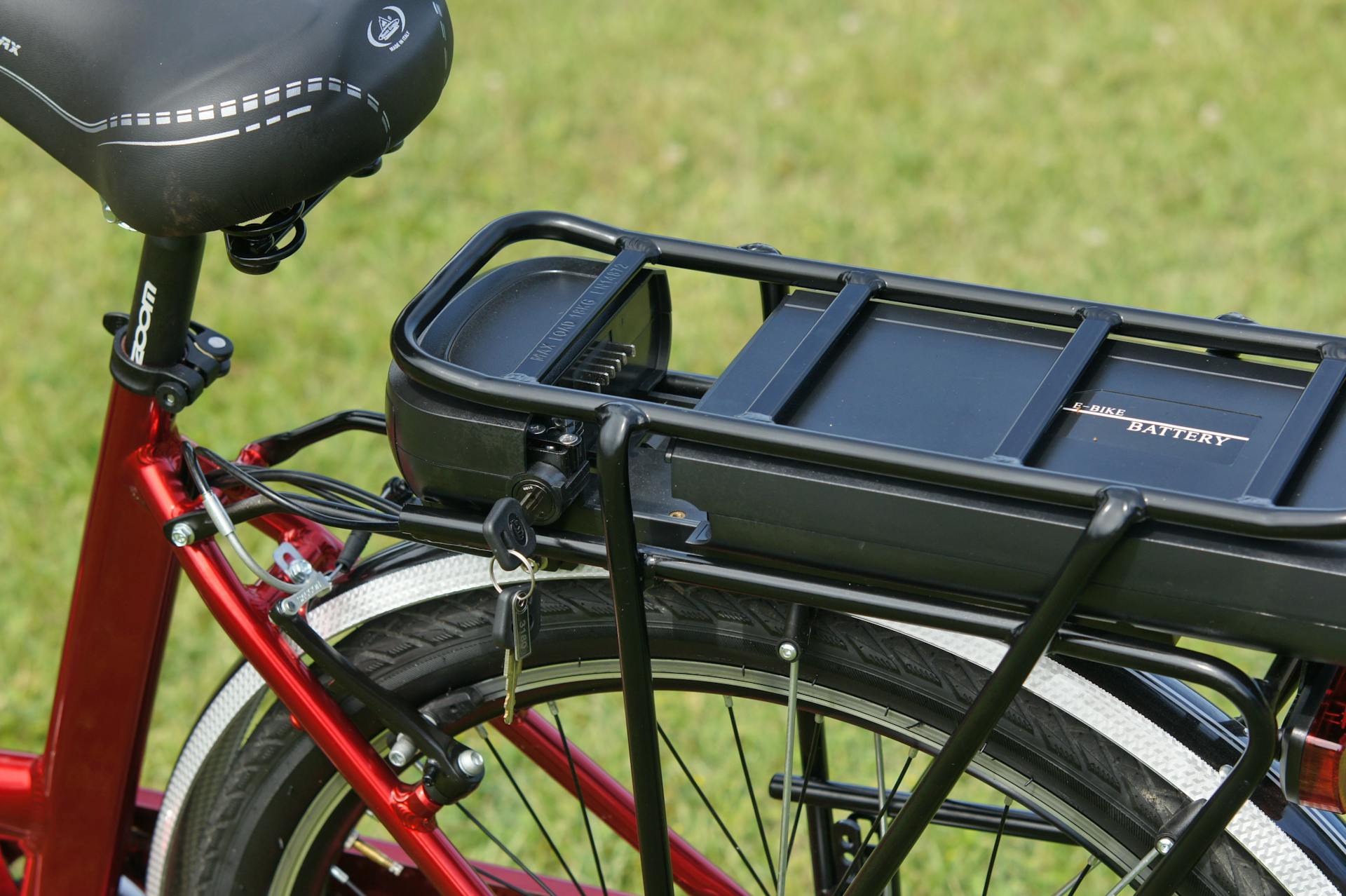 Detailed view of an electric bicycle battery mounted on a rear rack, highlighting the key-lock mechanism.