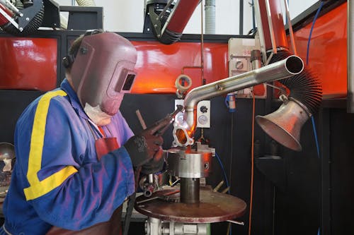 A Person Wearing a Welding Helmet Holding a Tool on a Steel Tube