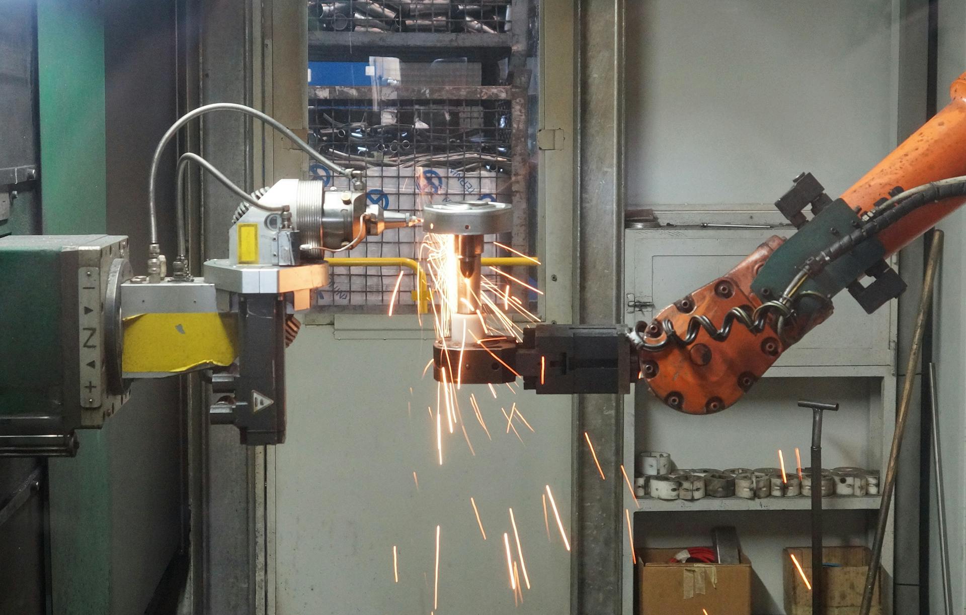 A robotic arm welding in an industrial setting, emitting bright sparks.