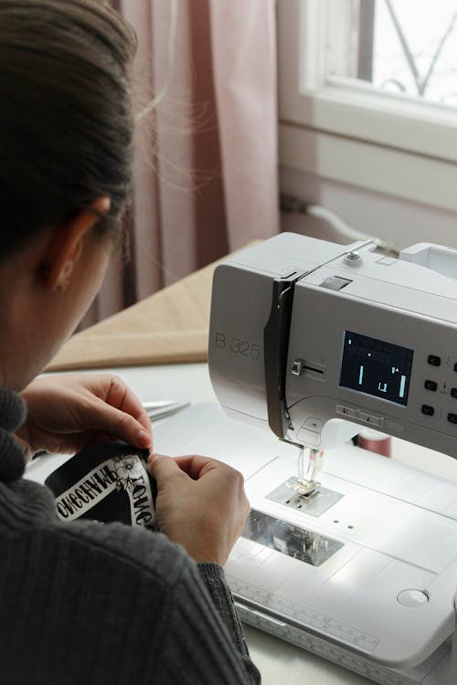 Person Sewing a Cloth in Front of a Sewing Machine