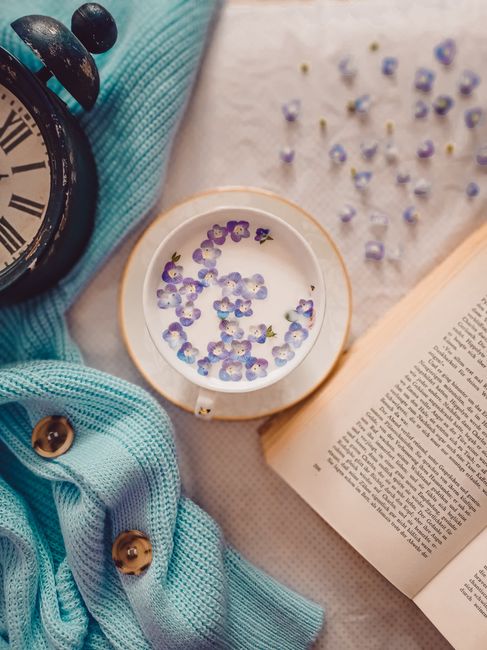 Delightful vintage flat lay featuring a cup of milk, flowers, and an open book.