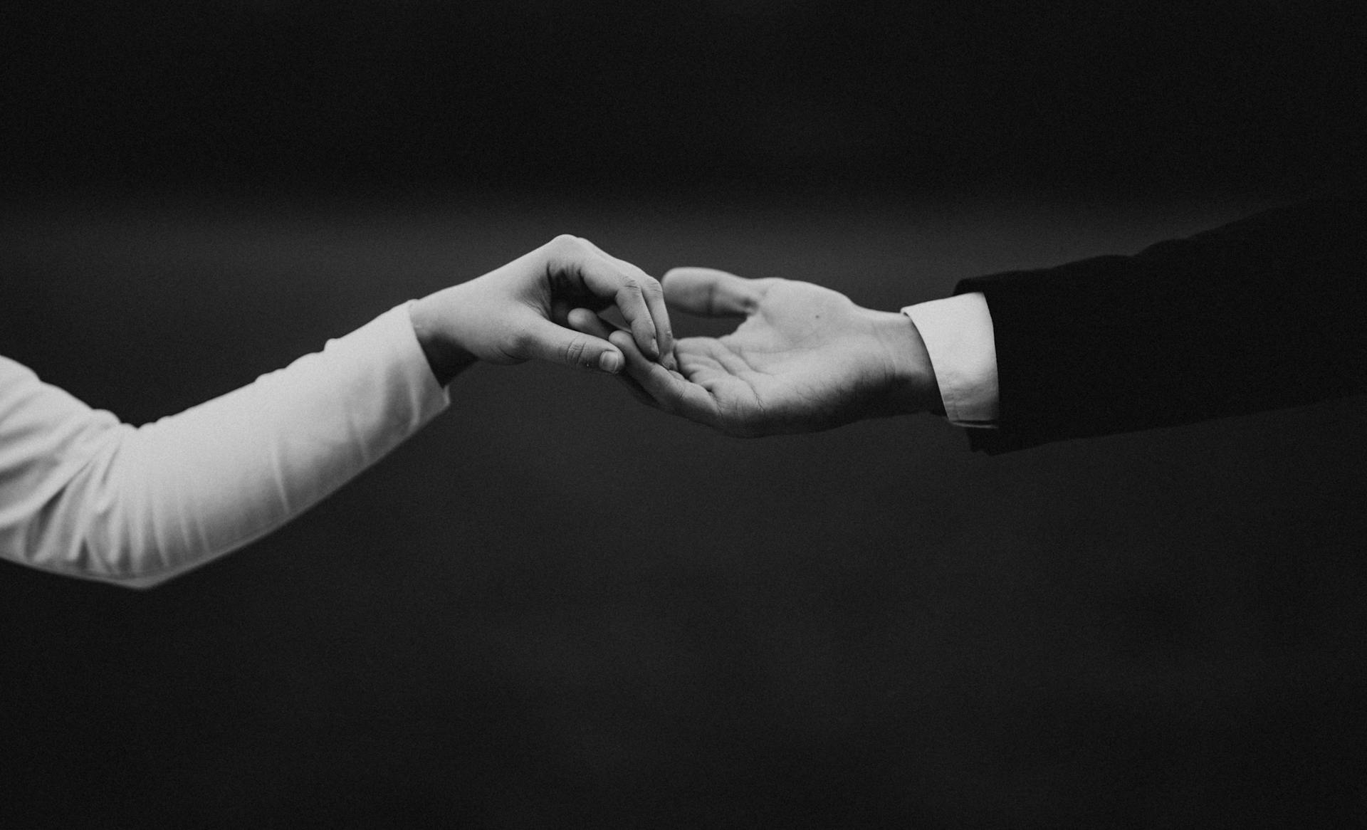 A striking black and white photo of hands holding symbolizing love and unity in a wedding setting.