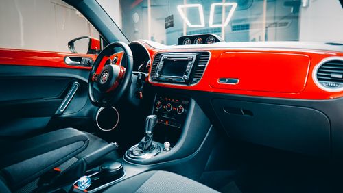 Free Detailed view of a modern car's stylish interior featuring a red dashboard and advanced console. Stock Photo