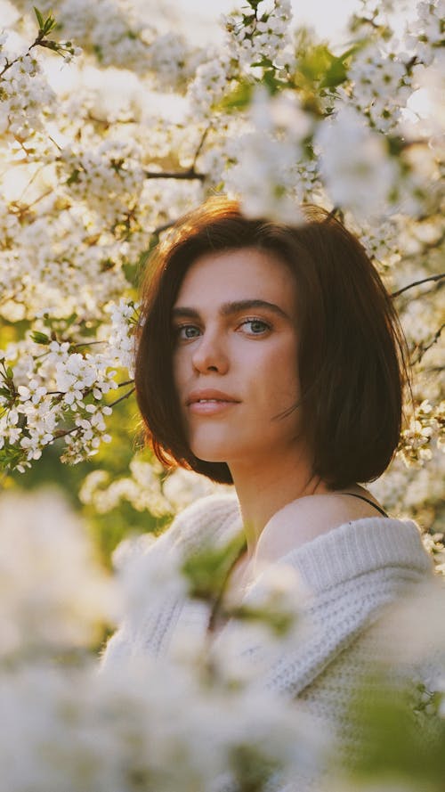 Portrait of Young Woman Among Blossoming Tree Branches 