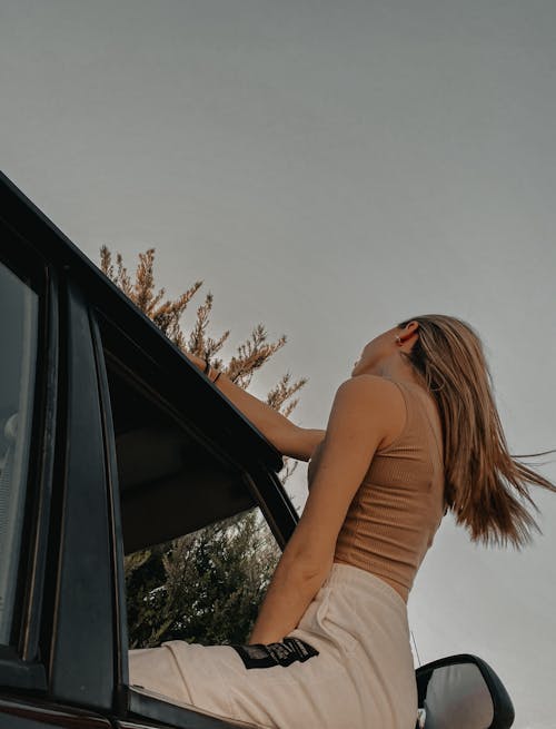 Back View Shot of a Woman Sitting on a Car Window