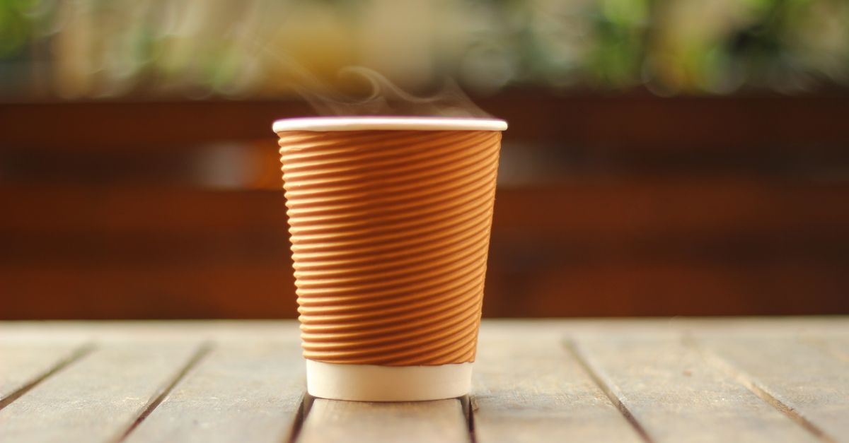 open Bible on a wooden table next to a steaming coffee cup, morning light