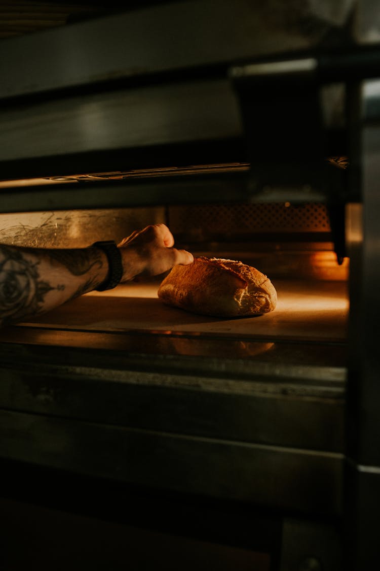 Man Reaching Into The Over For Bread