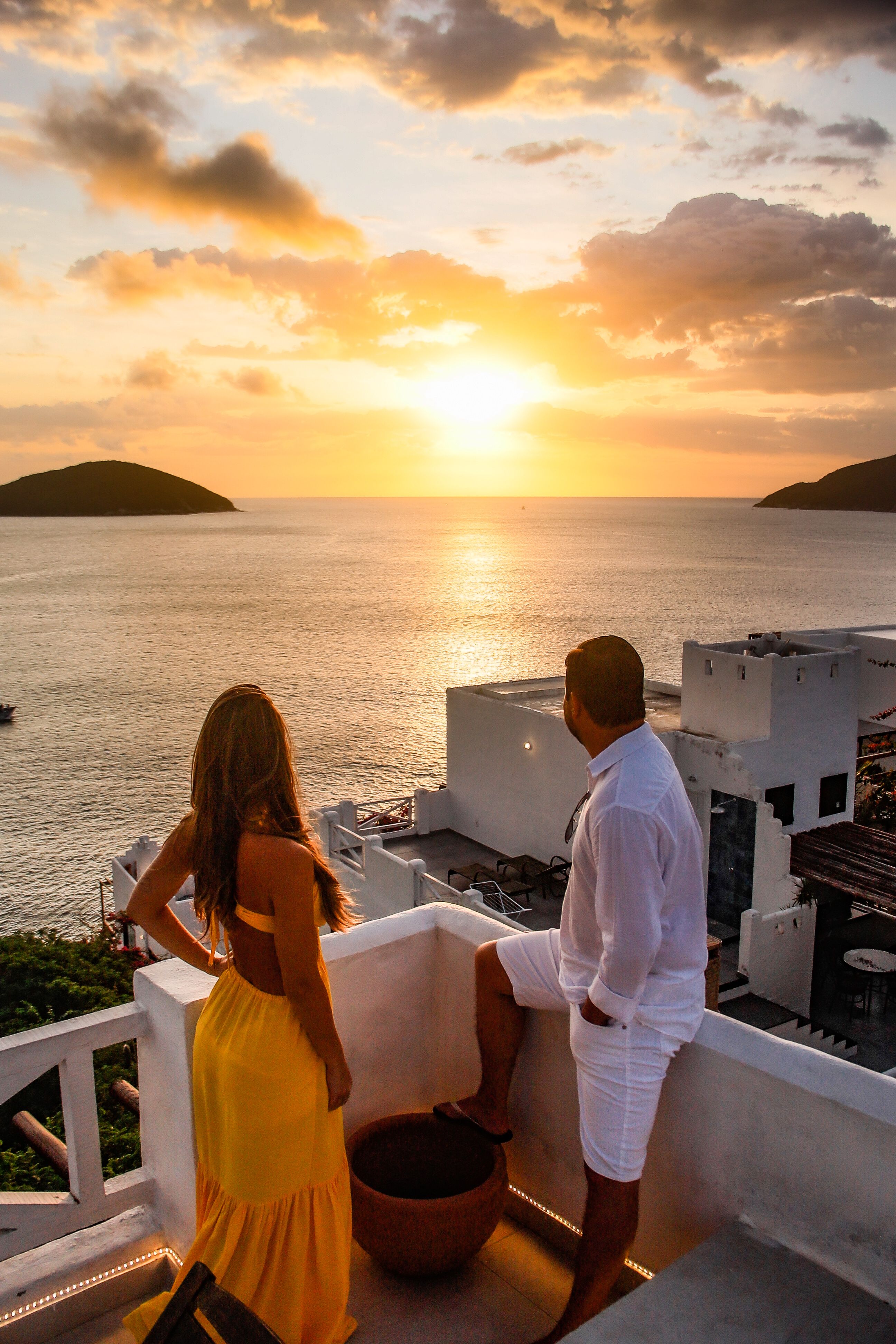 Backview of Couple standing on a Terrace looking and at the Sunset ...