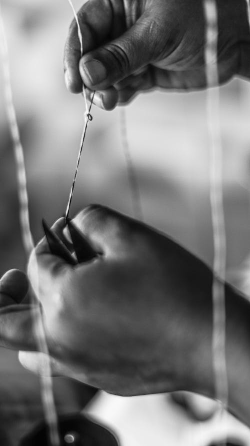 Free Grayscale Photo of a Person Tying a Sewing Thread while Holding Scissors Stock Photo