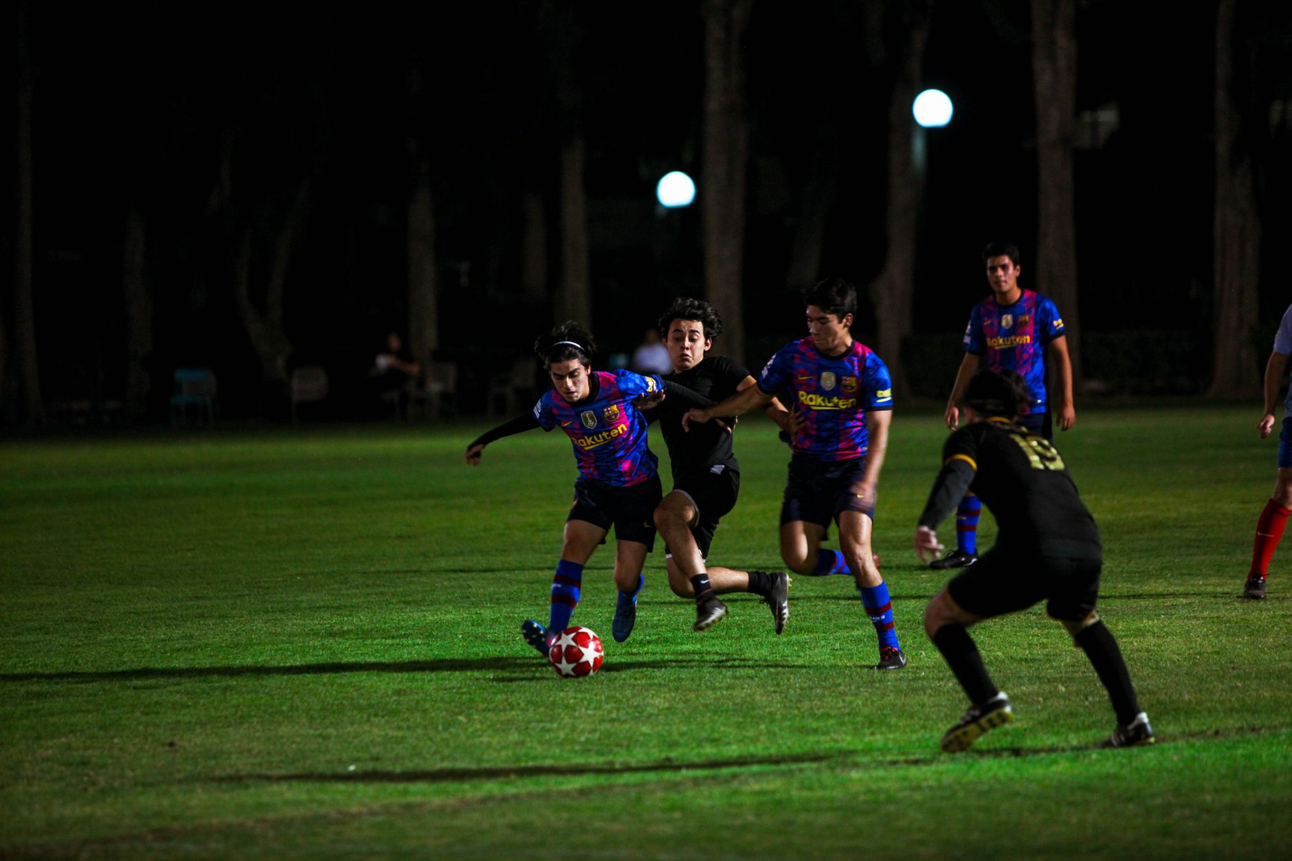 football players performing dynamic warm-ups on a wet training pitch beneath stadium floodlights