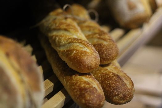 Close-up of freshly baked baguettes on a wooden shelf in a bakery.