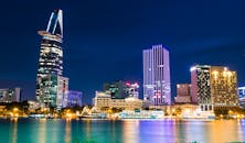 胡志明市的天际线在夜色中充满活力，波光粼粼的摩天大楼倒映在河中