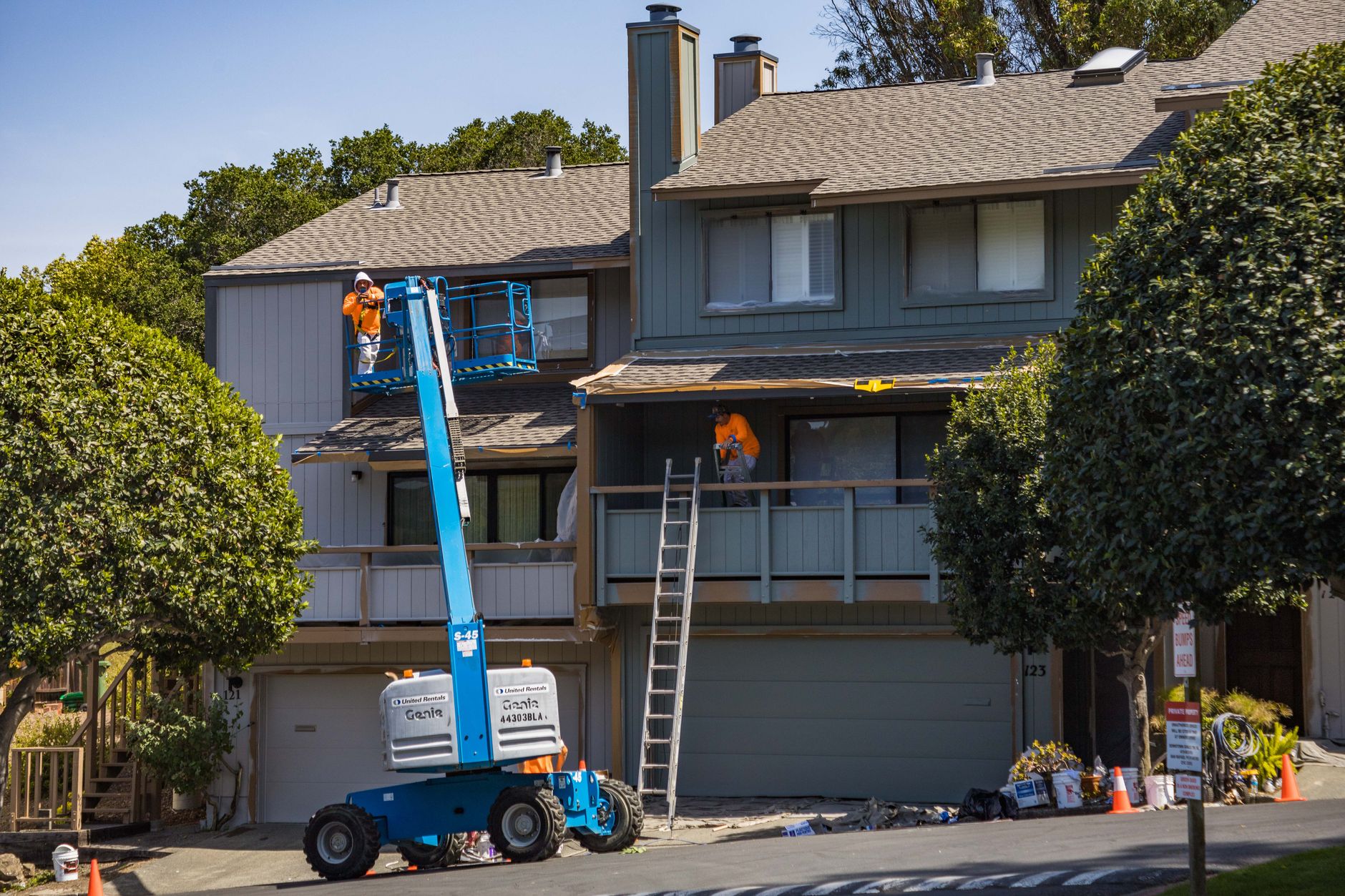 Professional painters on a hydraulic lift painting the exterior of a house in San Diego