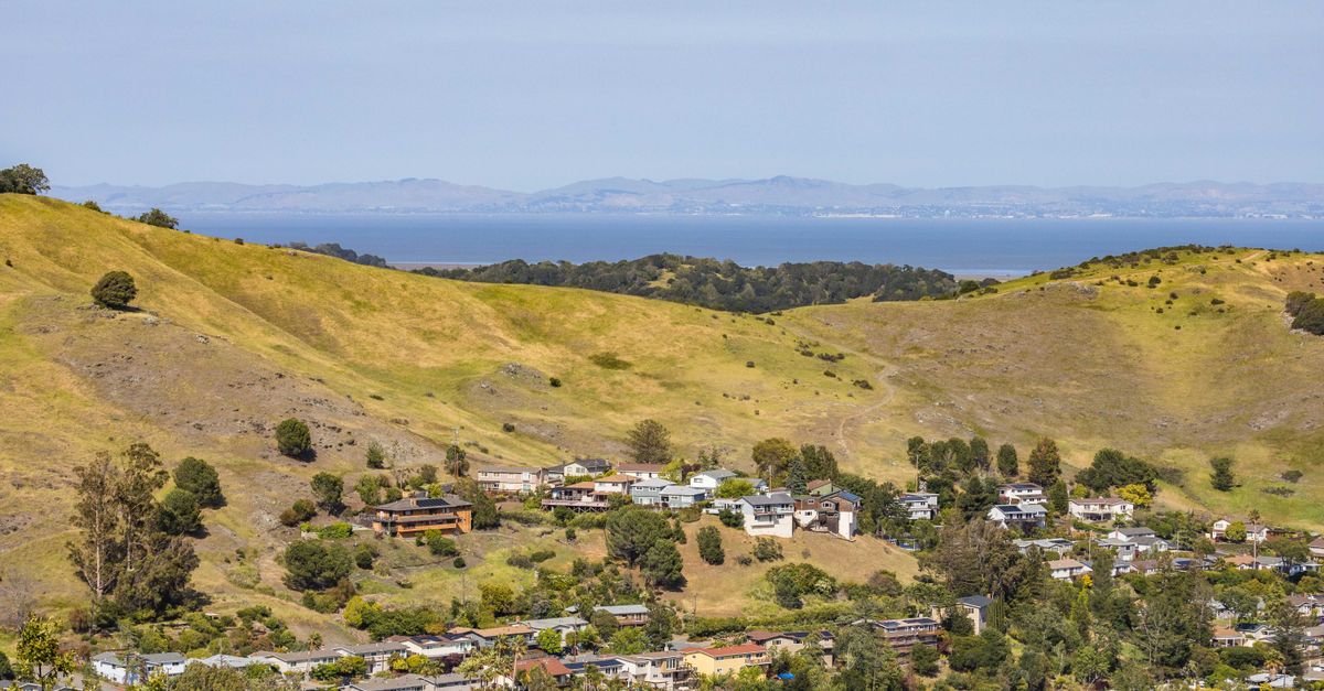 Scenic aerial view of rural landscape with hills, houses, and distant water.