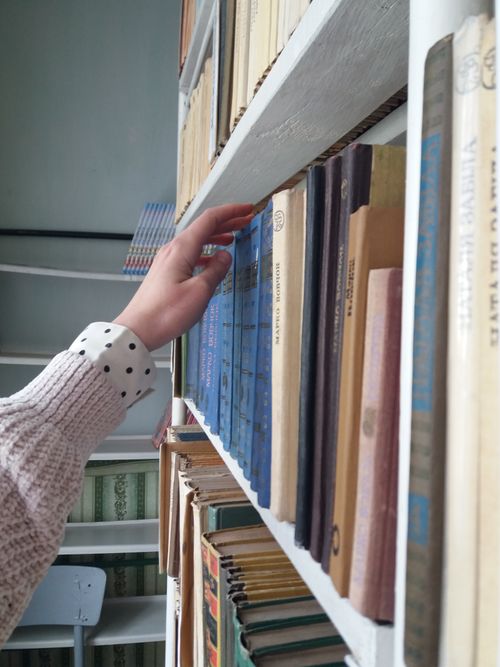Free Close-up of a person choosing a book from a library shelf, emphasizing education and literature. Stock Photo