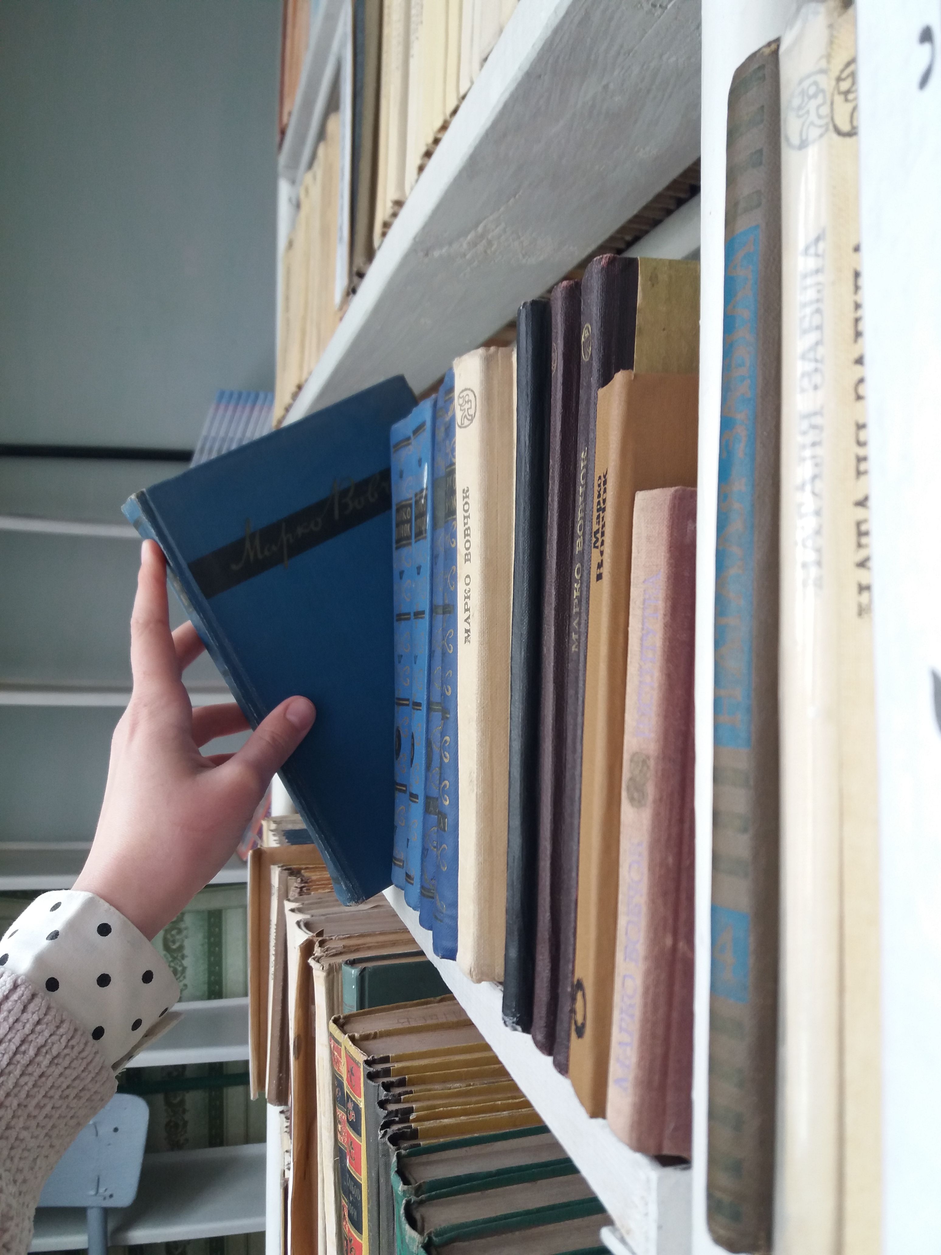 A Hand Getting the Book form the Wooden Shelf · Free Stock Photo