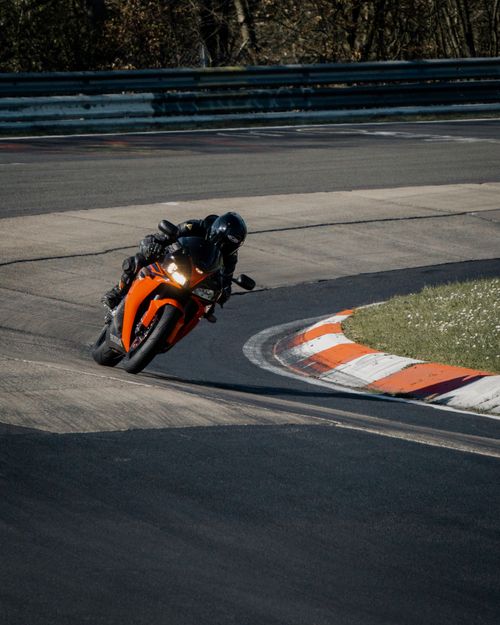 Free Close-up shot of a motorcyclist racing on a track, leaning into a curve with speed and precision. Stock Photo