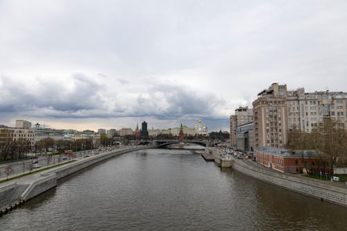 Body of Water Near Buildings Under Cloudy Sky