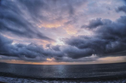 Captivating image of dramatic storm clouds over a tranquil sea at twilight.