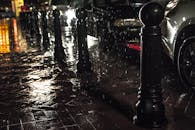 夜晚的城市街道上，雨水和闪闪发光的人行道反射着城市的灯光