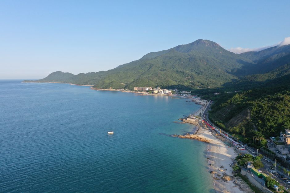 Breathtaking drone shot of the Shenzhen coastline with lush mountains and a serene beach.