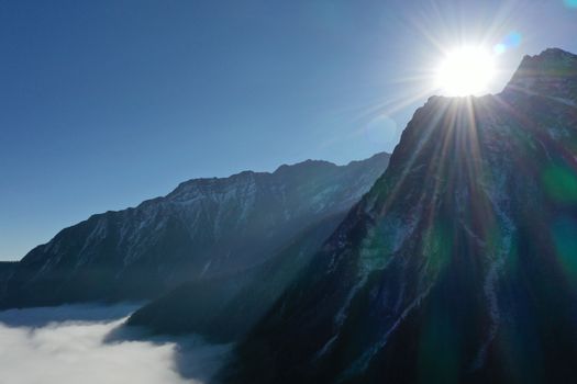 Majestic mountain range in Sichuan, China, captured with sunbeams over peaks under a clear blue sky.
