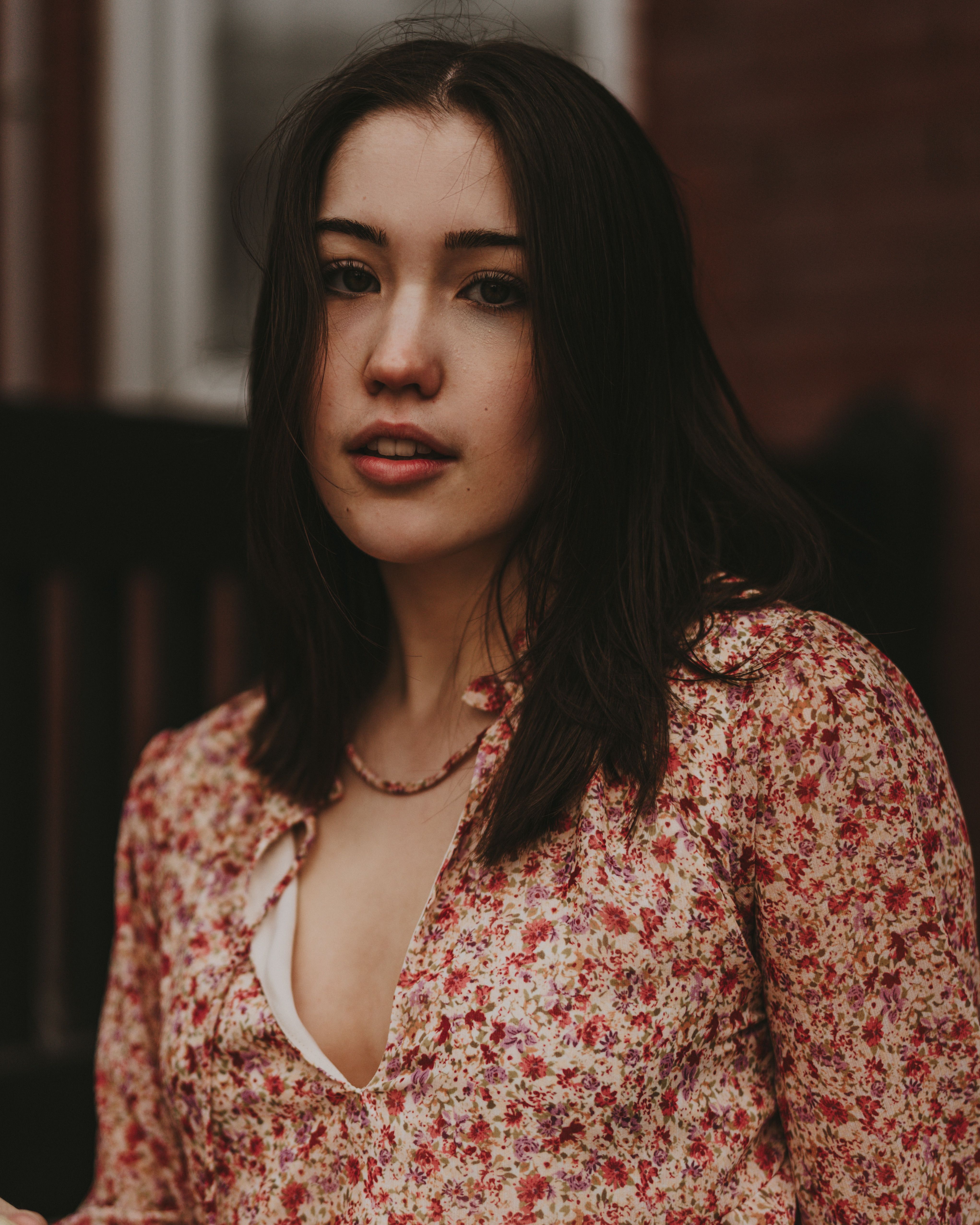 Beautiful woman in floral dress with soft, natural lighting outdoors.