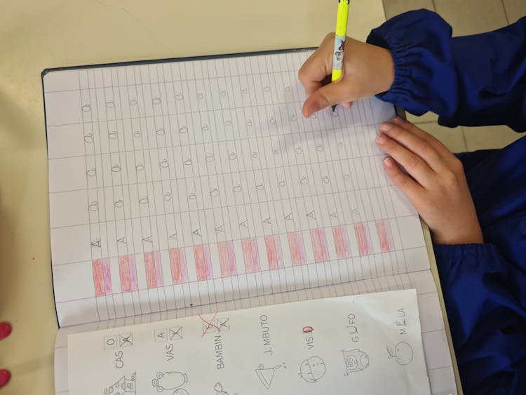 A Kid Writing On A Notebook