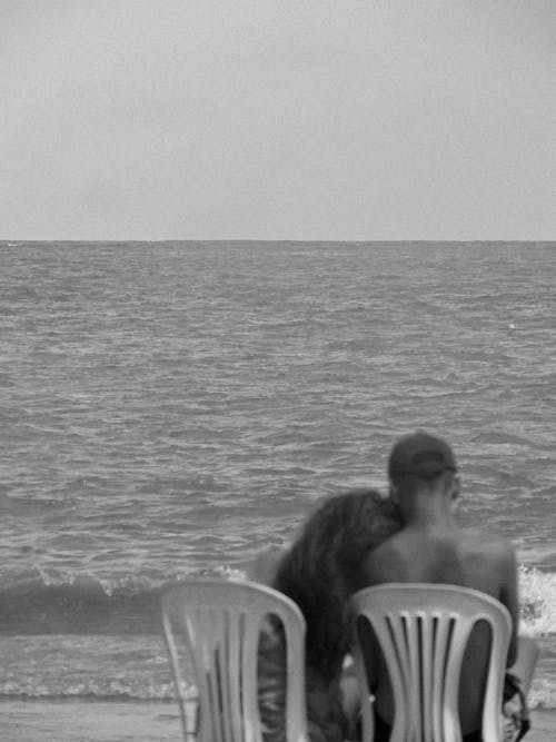 Backview of a Romantic Couple sitting beside the Sea 