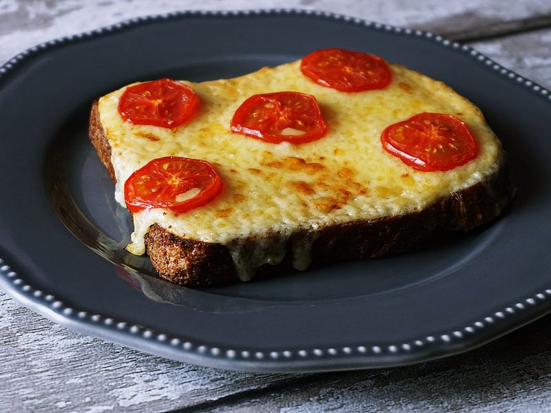 Delicious melted cheese and tomato toast on a rustic grey plate, perfect for breakfast or