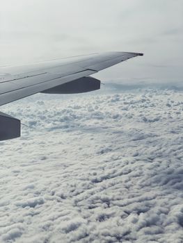 A calming view from an airplane window above fluffy white clouds, showcasing tranquility in flight.