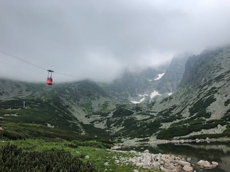 Exploring the breathtaking Vysoké Tatry with misty peaks, a serene lake, and a vivid red cable car.