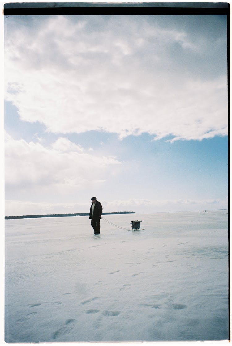 Man Walking In Snow And Pulling A Sled