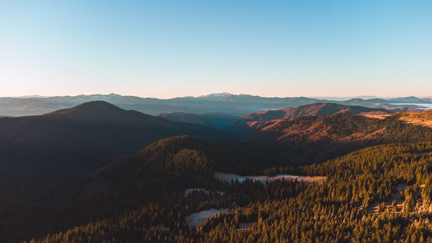 A breathtaking aerial shot capturing the vast expanse of the Carpathian Mountains under a clear blue sky.