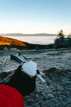 Person holding a drone against a frosty landscape in Holda, Romania, during winter sunrise.