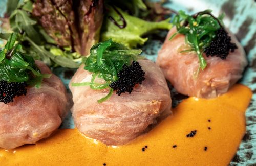 Free Close-up of gourmet tuna wraps topped with seaweed and roe in a rich sauce. Stock Photo