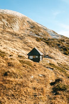A solitary cabin nestled in the mountains of Romania during fall, offering a tranquil escape.