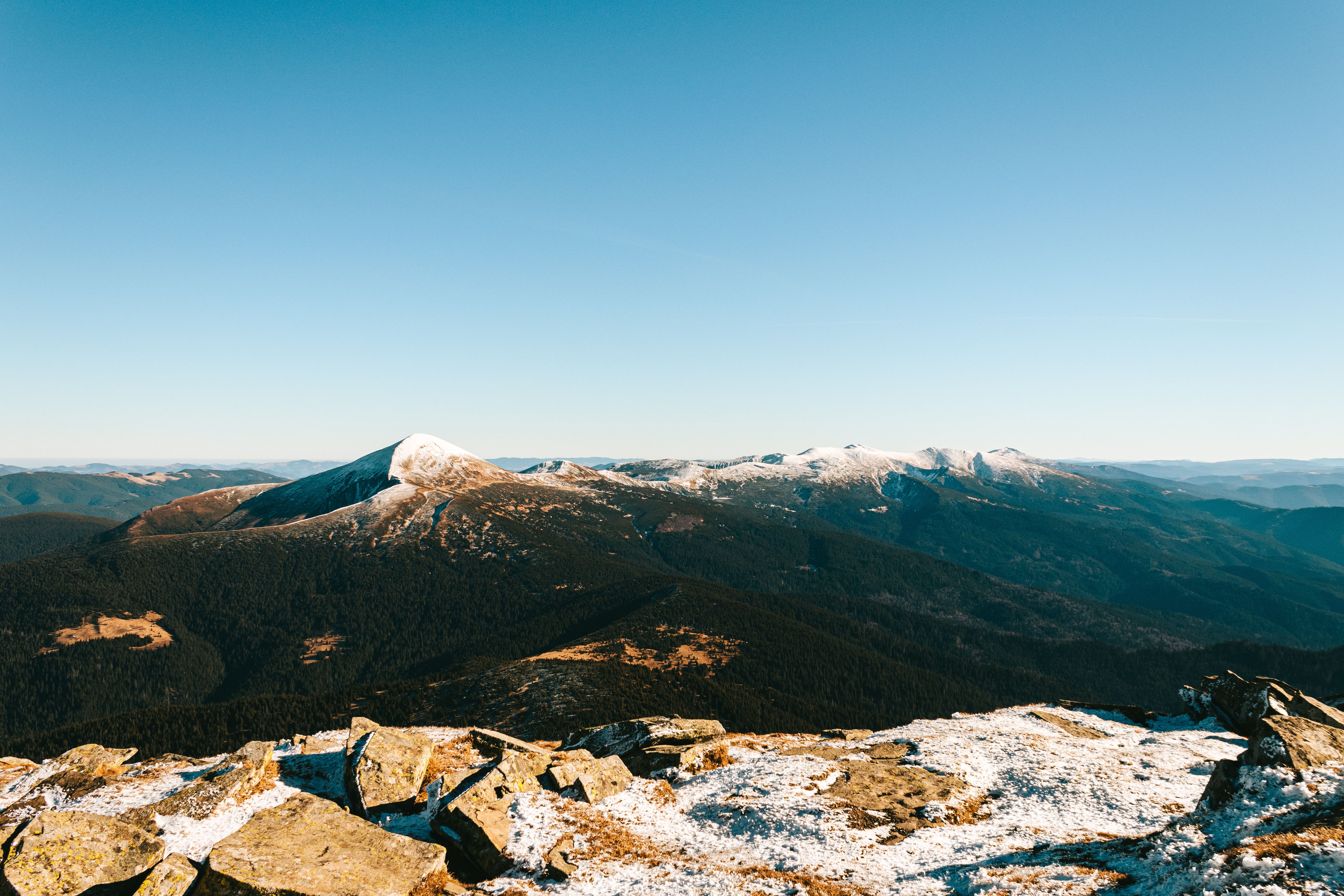 Stunning winter landscape of the Bucovina Mountains with snow-capped peaks under a clear blue sky.