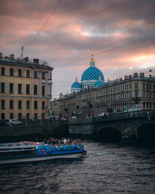 Free Capture the essence of St. Petersburg with sunset hues, a historic bridge, and boat cruising the Neva River. Stock Photo