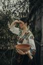 Woman in Embroidered Shirt Holding Ceramic Bowl