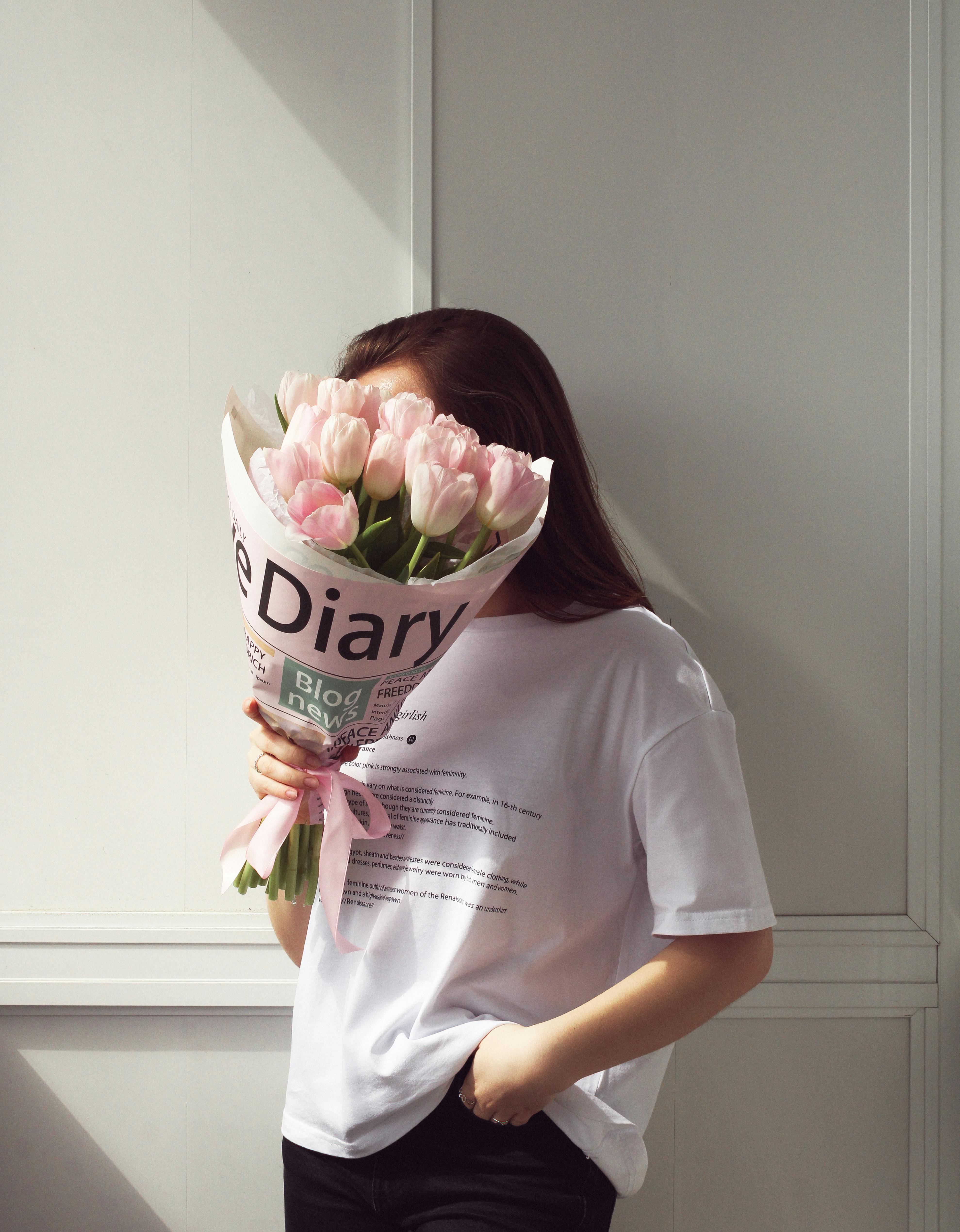 A woman in casual attire holds a bouquet of pink tulips, adding a touch of freshness and elegance.