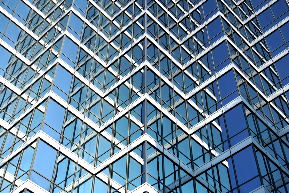 Close-up view of modern skyscraper facade with geometric glass panels and sky reflection.