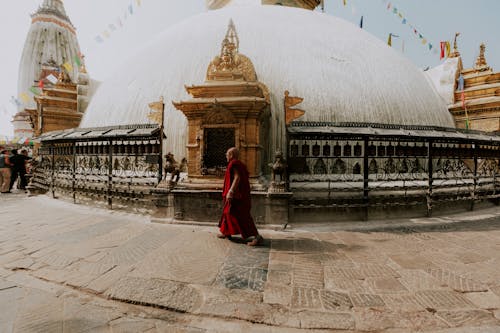 Photo of a Monk Walking Outside a Stupa