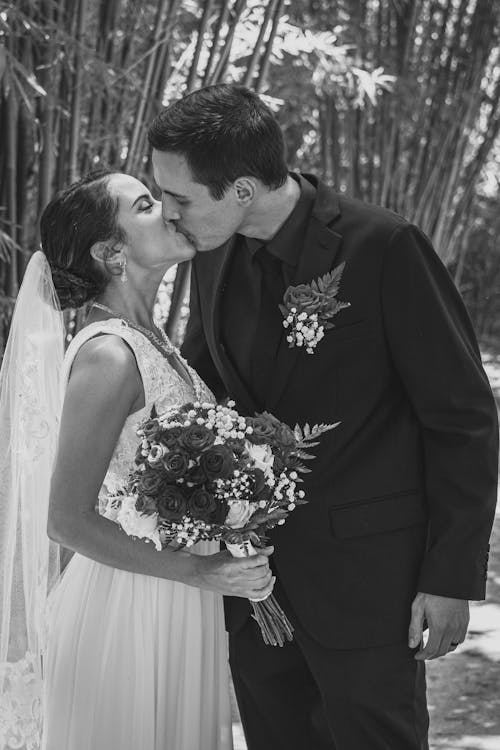 Free Man in Black Suit Kissing Woman in White Wedding Dress Stock Photo