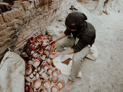 Free A potter arranging handcrafted clay pots in a traditional pottery workshop setting. Stock Photo