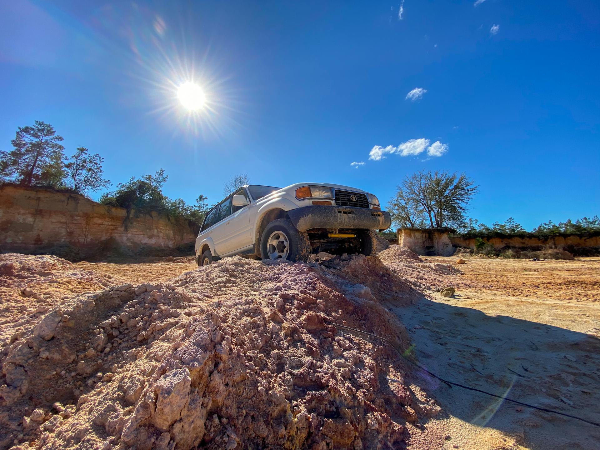 SUV driving on rugged terrain under a bright sunny sky, highlighting off-road capabilities.