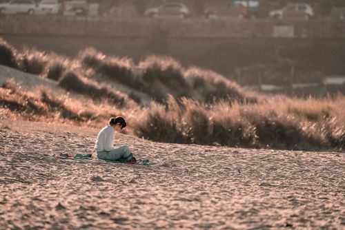 Free A woman enjoys peaceful solitude on a sunlit beach, surrounded by nature's calm beauty. Stock Photo