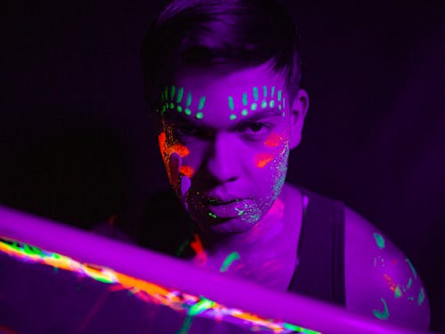 A Man in Black Tank Top With Green and Red Face Paint