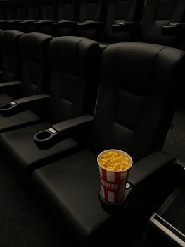 A bucket of popcorn in an empty cinema with black leather seats, creating a classic movie theater vibe.