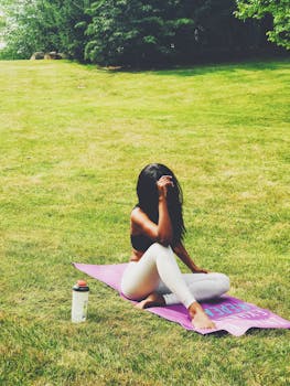 A young woman enjoys a peaceful yoga session outdoors on a sunny day, promoting healthy living.